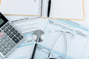 Healthcare paperwork with a calculator and stethoscope.
