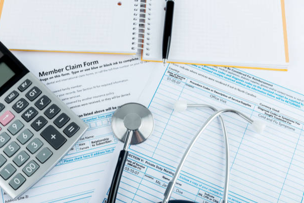 Healthcare paperwork with a calculator and stethoscope.