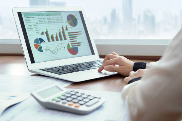 Person analyzing colorful financial charts and graphs on a laptop, with a calculator nearby.