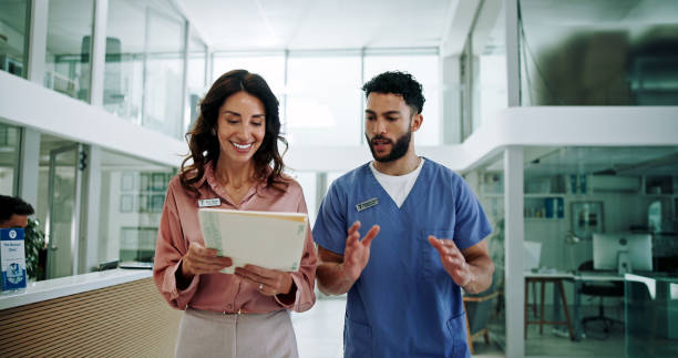 Two healthcare professionals walking and discussing patient files in a modern clinic.