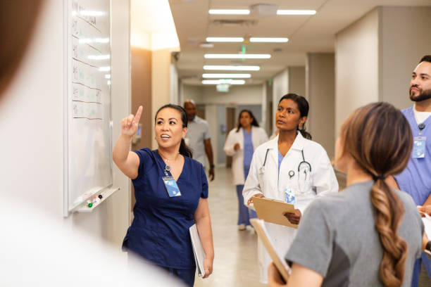 Medical team discussing patient information at a whiteboard in a hospital hallway.