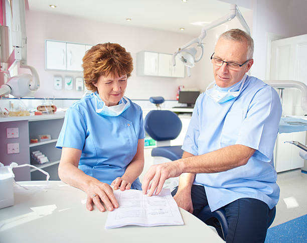 Two dental professionals reviewing a document in a bright dental office.